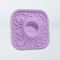 A lavender purple silicone mold with a central circular cavity and embossed doodle-style graphics, shown on a plain white background.